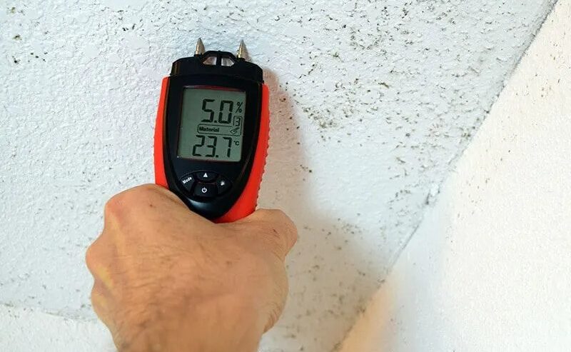 Technician inspecting a wall cavity with a moisture meter in an Ormond Beach home