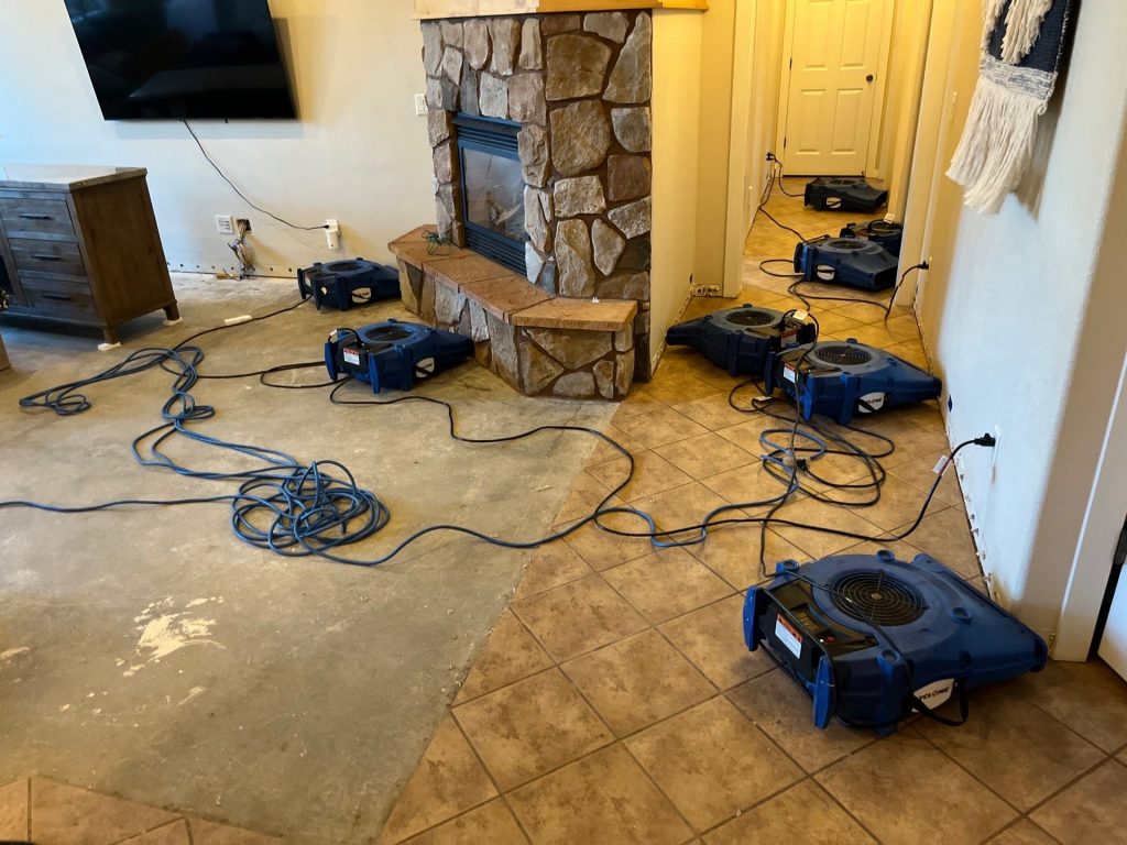Restoration professional setting up industrial air movers and a dehumidifier in a flooded kitchen