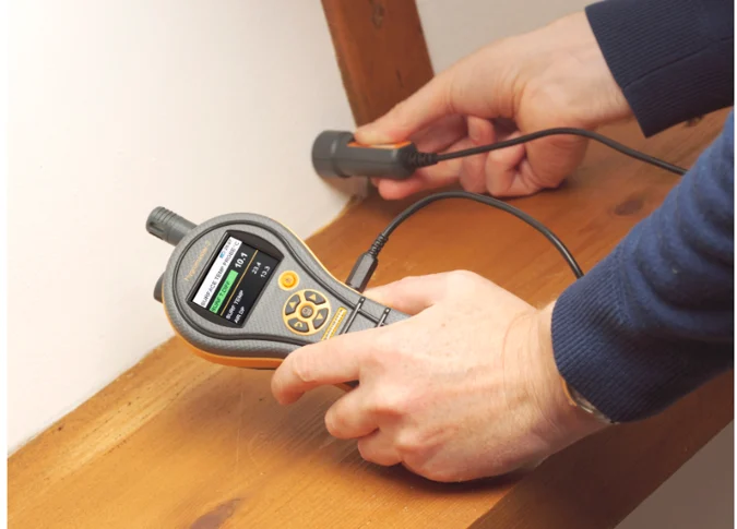 Water mitigation technician taking moisture readings from a concrete slab floor in an older Ormond Beach FL home using professional detection equipment