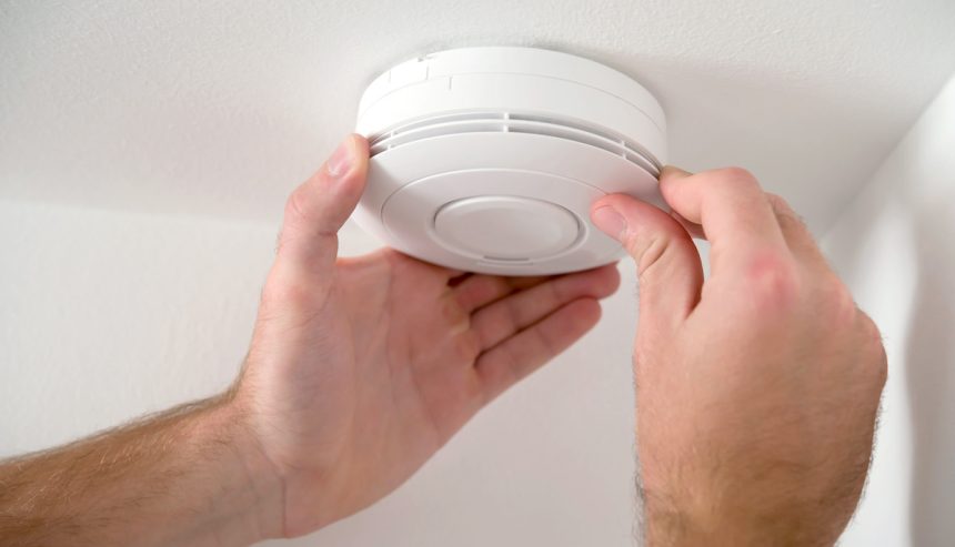 Close up of carbon monoxide detector being adjusted by a man.