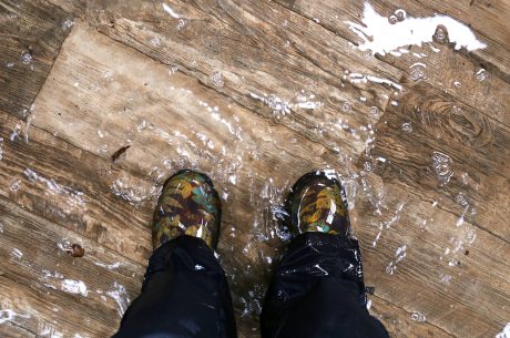 Someone standing on a hardwood floor with about an inch of water on it.