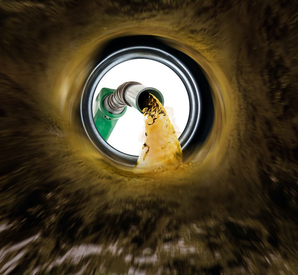 Fuel being poured from a gas nozzle into a tank, emphasizing gasoline safety and handling precautions.