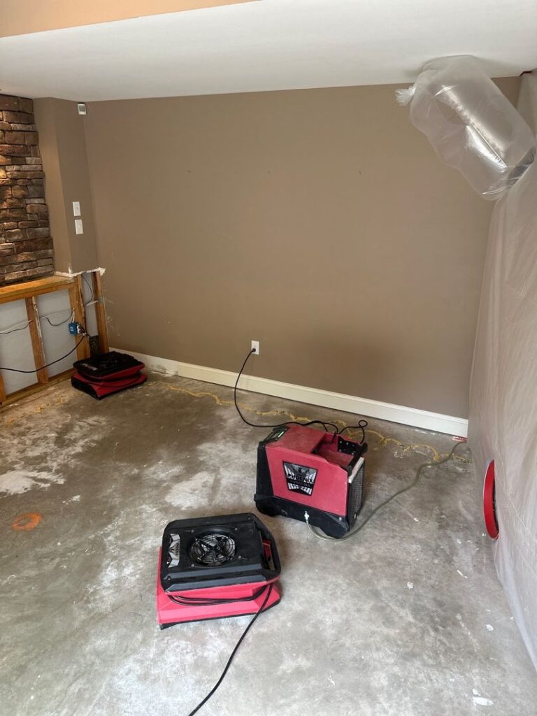 Water damage restoration in progress with drying machines and a containment barrier.