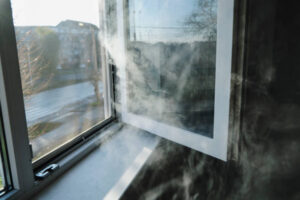 White smoke billows from a partially open window, obscuring the view of the street outside