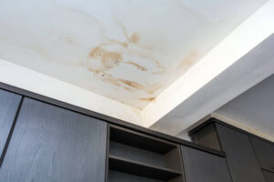 A white ceiling displays multiple brown water stains above dark modern cabinets. a common reason for mold growth in peoria homes