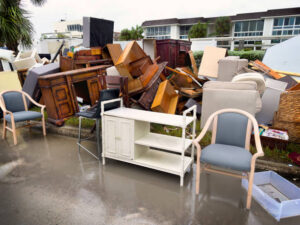 Damaged furniture and household debris are piled on a wet street after a storm. need for flood damage restoration in stanford