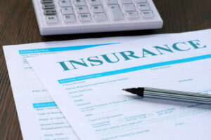 A pen rests on an insurance application form with a calculator in the background.