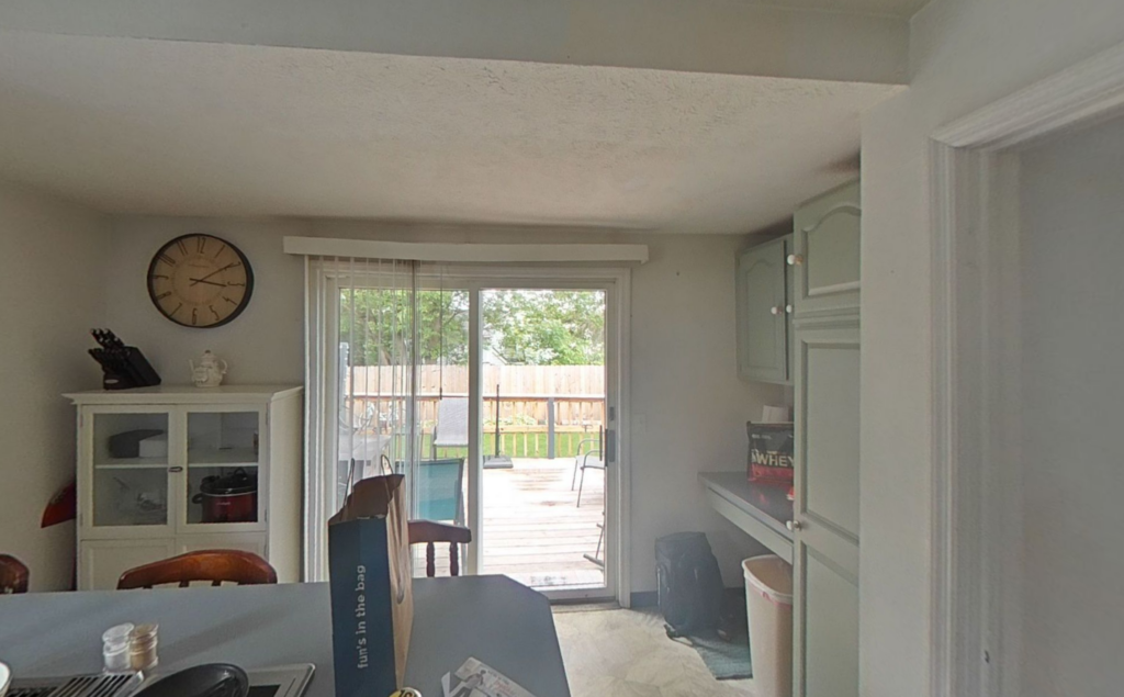 A bright home interior with kitchen cabinets and a wall clock, overlooking a backyard deck through a sliding. water damage affects air quality in homes