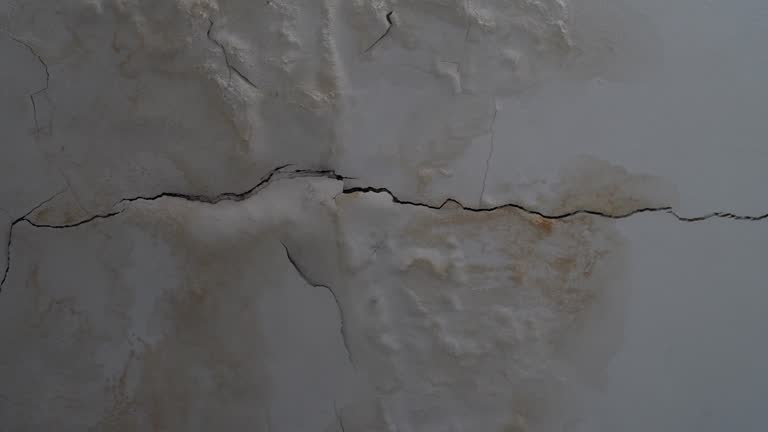 Cracked and water-stained ceiling showing signs of severe moisture damage and peeling paint. TITLE: professional restoration in Peoria