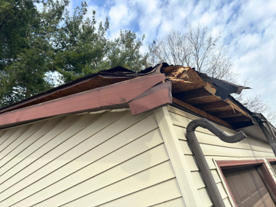 Severe structural roof damage on a residential garage before reconstruction services by PuroClean of Plymouth. Exposed wood and broken shingles highlight the urgent need for professional storm damage repair and reconstruction.