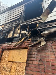Residential fire mitigation is shown in a heavily destroyed garage structure with collapsed walls, exposed framing, and extensive fire-related debris scattered across the ground. The interior is charred and filled with burned materials, highlighting severe structural loss and smoke damage throughout the building.