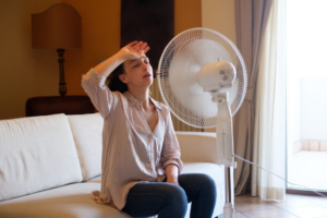 woman sitting by a fan to stay cool
