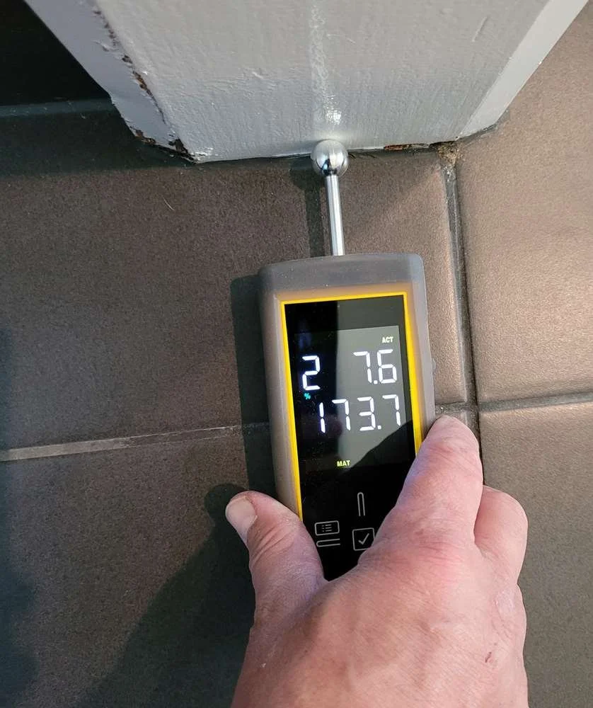 Moisture meter being used on drywall to detect hidden water