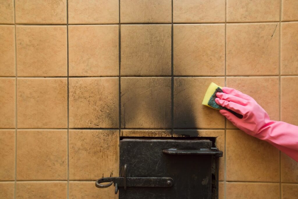 echnician wiping soot from a white painted wall using a professional dry cleaning sponge