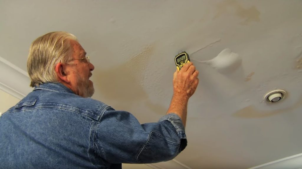 Technician using a handheld moisture detector on an interior wall