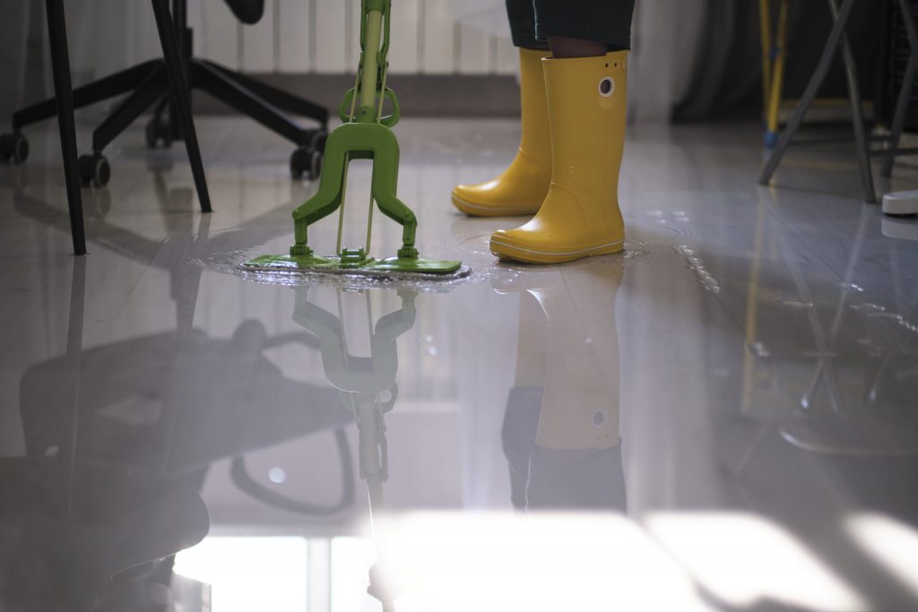 Technician using water extraction equipment on soaked flooring