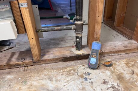 Technician assessing water damage near a baseboard inside a Rancho Cucamonga home