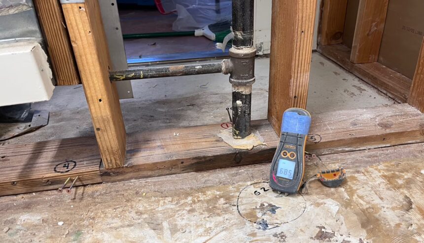 Technician assessing water damage near a baseboard inside a Rancho Cucamonga home