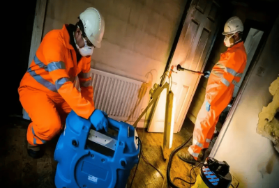 Professional fire damage restoration team in high,visibility gear assessing a fire,damaged commercial interior warehouse in Rancho Cucamonga