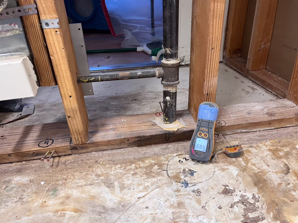 Technician assessing water damage near a baseboard inside a Rancho Cucamonga home
