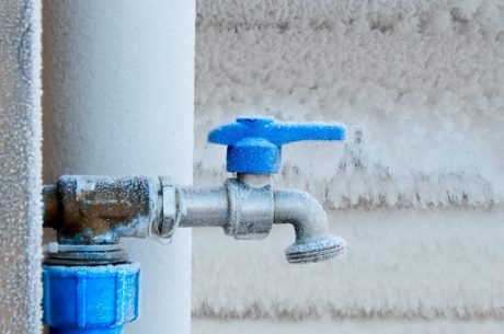 Frozen hose bib on the side of a house during cold weather