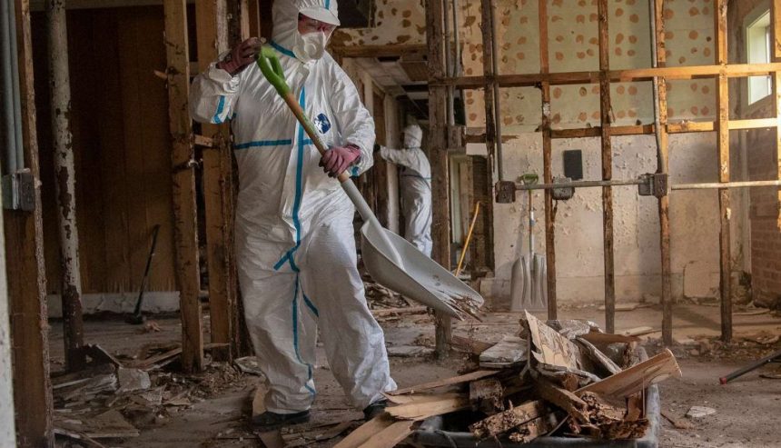 Professional fire damage restoration team in protective gear assessing a damaged interior in a Ridgewood, NJ home.