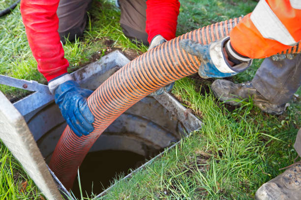 Workers in gloves guide a large orange hose into an open manhole for Sewage Cleanup in Westwood NJ: Urgent 24/7 Local Help