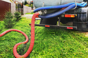 A red hose from a septic vacuum truck lies on green grass, ready for Sewage Cleanup in Emerson NJ: Fast, Safe 24/7 Help