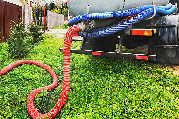 A red hose from a septic vacuum truck lies on green grass, ready for Sewage Cleanup in Emerson NJ: Fast, Safe 24/7 Help