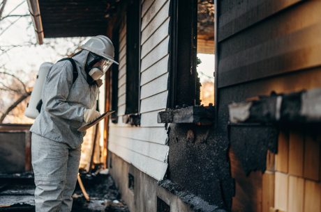 Fire restoration inspection professional assessing structural fire damage to a home’s exterior and foundation