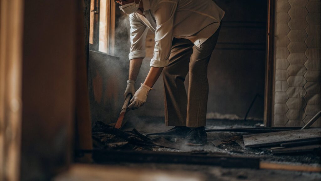 Homeowner attempting DIY fire damage cleanup, highlighting the risks and safety hazards of improper fire restoration
