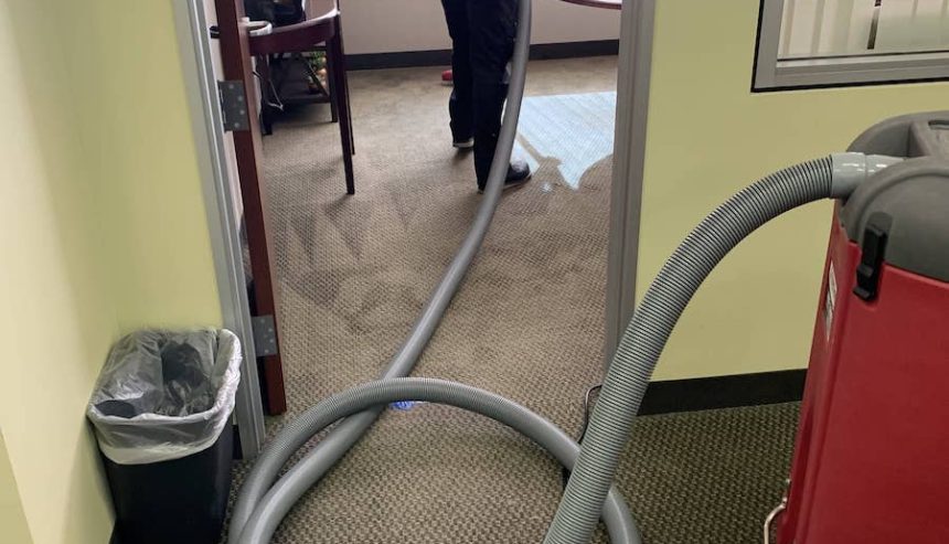 PuroClean technician drying conference room after flooding caused by broken irrigation sprinkler