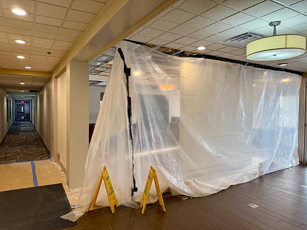 A hotel hallway leads to an area under renovation, sealed off by clear plastic sheeting and caution