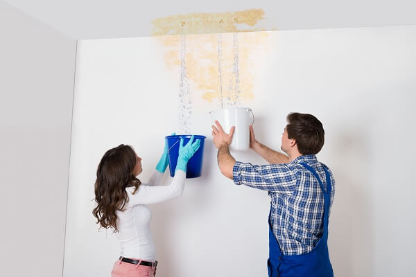 Homeowner inspecting a ceiling water stain caused by a leaking roof