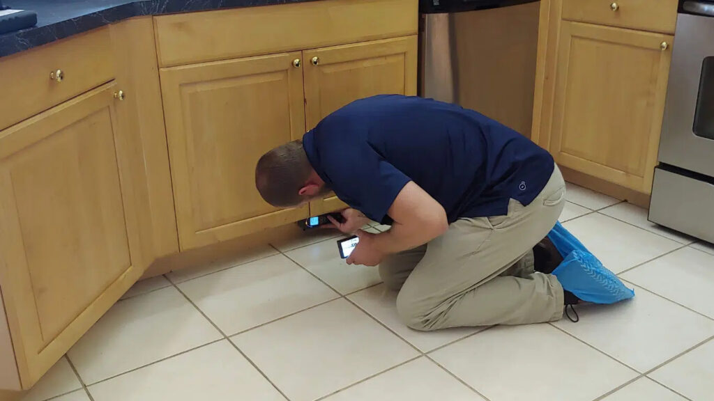 Technician using moisture-detecting tools on a Sarasota home’s tile flooring