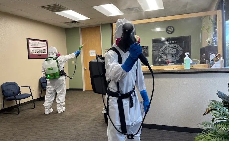 Technician wearing full PPE preparing equipment for a biohazard cleanup scene