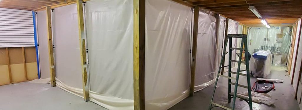 Remediation team performing mold removal behind a containment barrier