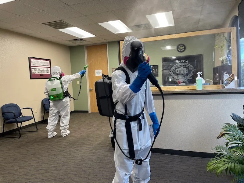 Technician wearing full PPE preparing equipment for a biohazard cleanup scene