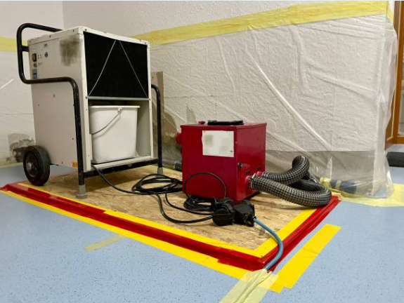 Multiple industrial dehumidifiers and air movers set up in a room during restoration.
