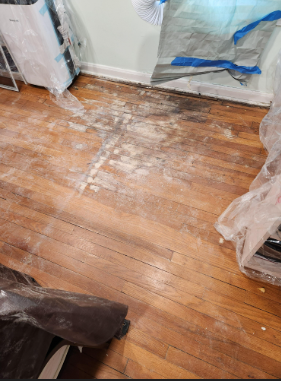 A flooded Victorian-era home interior in a Pennsylvania borough; aged hardwood floors warped by water, antique cabinetry showing moisture damage, realistic emergency scene without being graphic| Insurance Claim Restoration in Ambler
