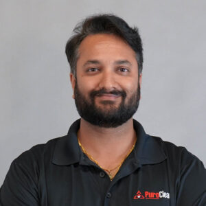 A smiling man with a beard wears a black PuroClean polo shirt and a gold