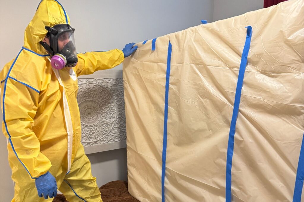 restoration professionals doing biohazard cleanup holding a wrapped bed mattress
