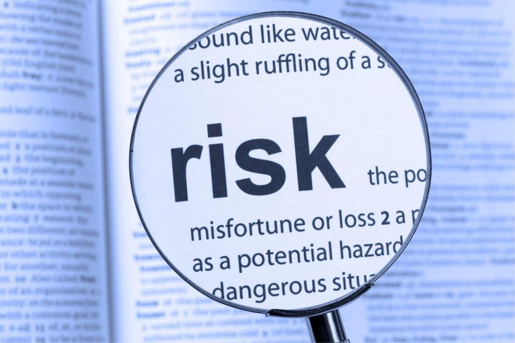 a magnifying glass above a dictionary looking at the word risk