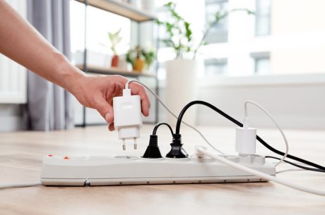 Hand plugging something into a white power strip.