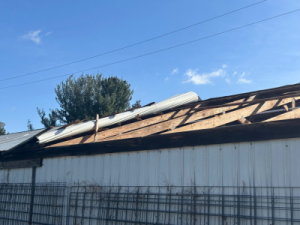 Storm-damaged roof with missing panels and exposed wood structure, highlighting the urgent need for structural repair services in Waterford Township.