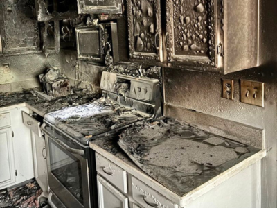 Kitchen fire damage restoration scene in a Waterford Township home showing extensive soot, burned cabinets, and smoke-damaged appliances.