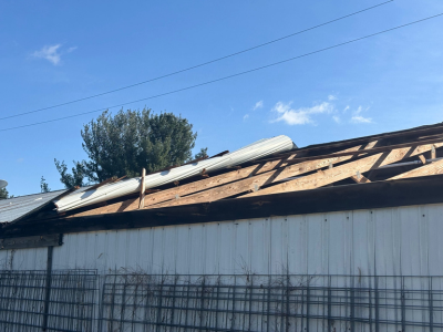 Storm-damaged roof with missing panels and exposed wood structure, highlighting the urgent need for structural repair services in Waterford Township.