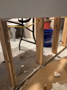 Exposed wooden wall studs and wet concrete floor in a basement undergoing restoration after significant water damage.