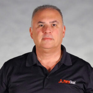 A man in a black polo shirt with the PuroClean logo, standing against a gray background.