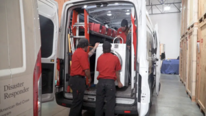American Red Cross team members load a washing machine into a disaster response van. TITLE